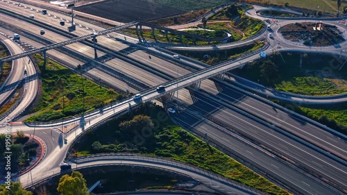 Aerial perspective of complex highway junction and roundabouts. Low angle sunlight over multi-level road intersection with ramps, bridges and long shadows.