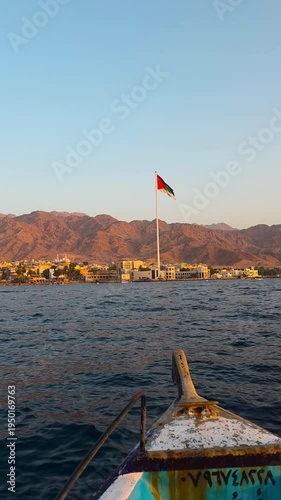 Wallpaper Mural POV vertical footage from a glass boat approaching the Arab Revolt Flag on the Aqaba waterfront, Jordan, with calm sea, coastal cityscape and warm sunset light Torontodigital.ca