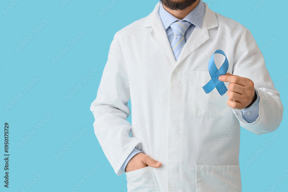 Naklejka premium Male doctor with blue ribbon on color background. Prostate cancer awareness concept