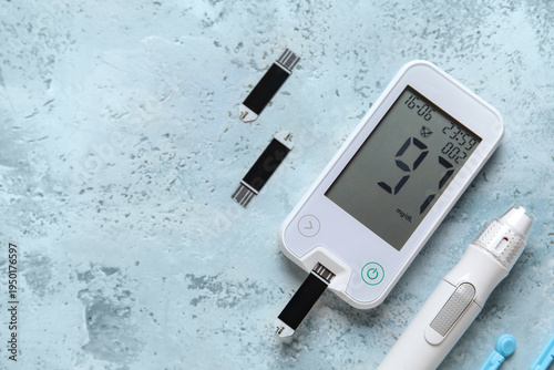 Photos Glucometer with lancet pen and test strips on blue grunge background