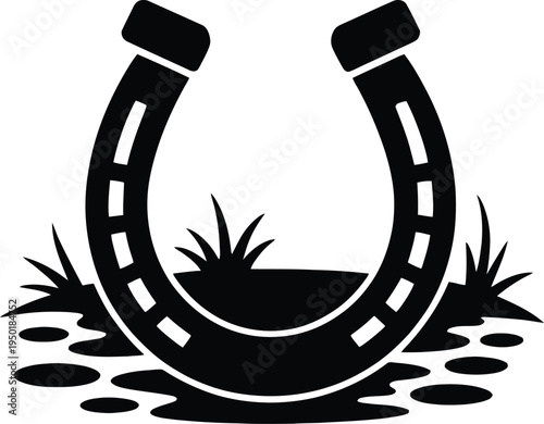 A horseshoe resting in muddy ground with small grass sprouts growing around it.