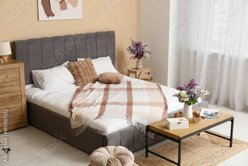 Interior of bedroom with bench and lilac flowers in vases