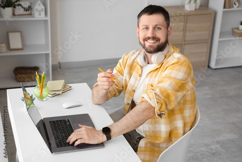 Young man working with laptop at desk in office