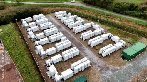 Aerial view of rows of battery energy storage systems contrasting with the green grass, creating an industrial landscape, Burwell, United Kingdom.