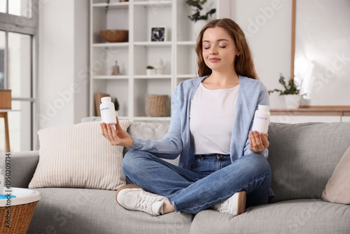 Fotografija Young woman with vitamin B pills meditating on sofa at home