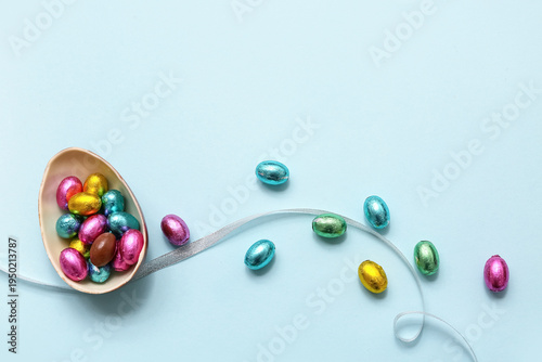 Chocolate Easter eggs in foil and ribbon on blue background