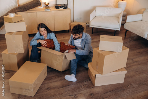 Fotografie Lovely couple unpacking cardboard boxes together in a new apartment after moving