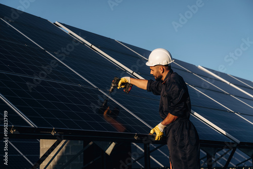 Crystal clear surface, installation, using tool. Male solar engineer examining photovoltaic panels at a power station