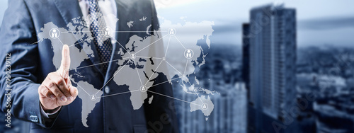 A businessman in a suit interacts with a digital world map overlay, illustrating global connectivity, international business networking, and communication technology against a city background