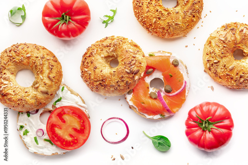 Various bagels, with smoked salmon and tomato and onion, overhead flat lay shot on a white background