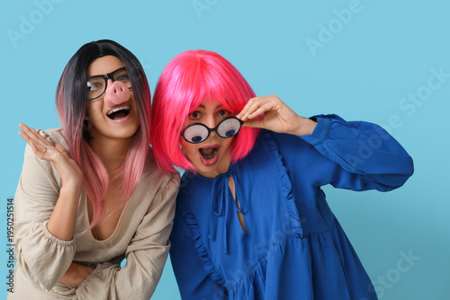 Fényképezés Beautiful young shocked women in funny disguise on blue background