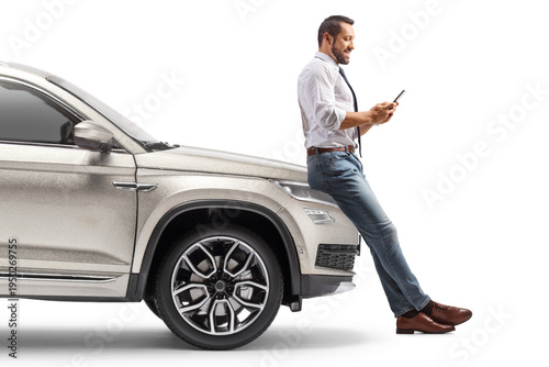 Man leaning on a car and using a mobile phone