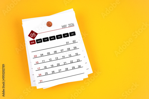 May 2026 calendar page with wooden push pin on yellow, position with copy space.