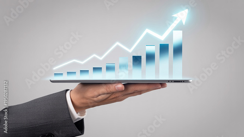 Businessman holding tablet with glowing graph and arrow on screen showing growth