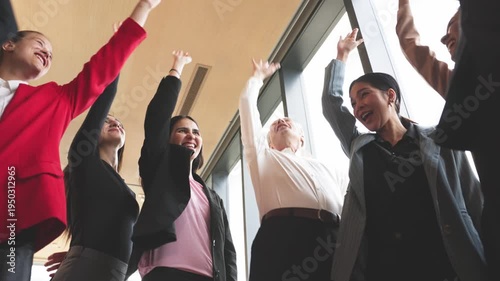 Diverse group of business professionals placing hands together in team unity gesture during meeting in modern office.