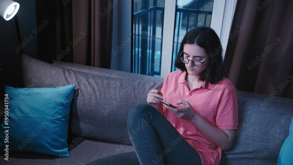 Obraz premium Young Woman Using Smartphone on Couch at Home, have fun and enjoy