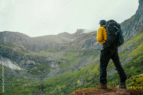 Man with backpack from behind with mountain background in Nordic Norway