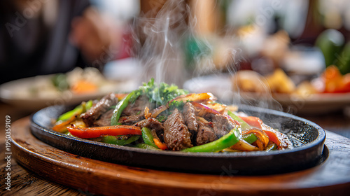 A plate of beef and vegetable fajitas on a hot skillet