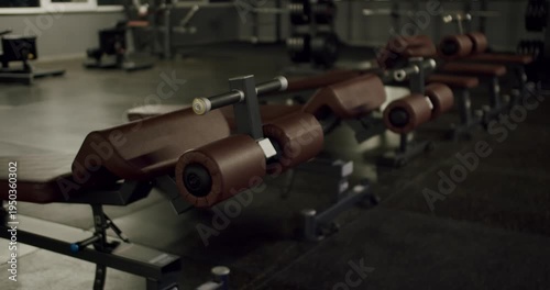 Empty fitness club with a row of professional hyperextension benches ready for a workout. Athletic, bodybuilding, and fitness concept with no people in a modern gym training facility