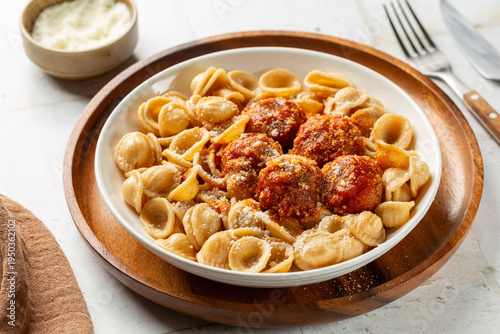 Whole grain italian pasta orecchiette with meatballs and tomato sauce, grated parmesan cheese. Homemade meal.
