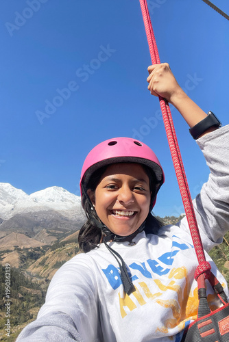 Happy girl ziplining in mountain valley landscape. UGC