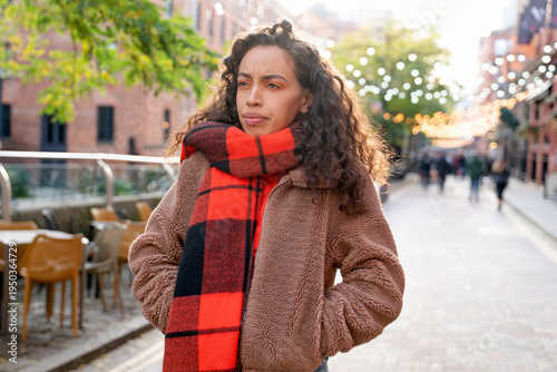 Woman walks in city street during fall with trees and lights in background