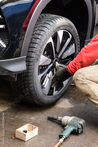 Mechanic performs tire maintenance on a vehicle in a workshop in the morning hours with tools and equipment nearby