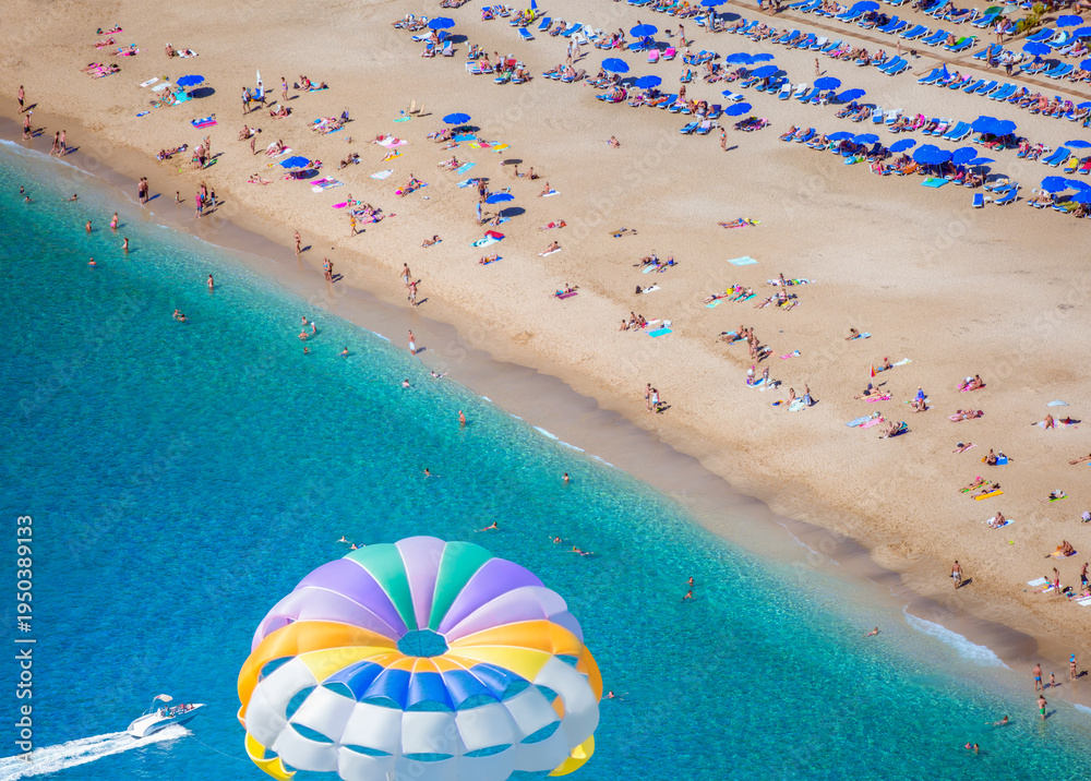 Fototapeta premium Flying on a colorful parachute behind a boat on a summer holiday by the sea in the resort - Alanya, Turkey