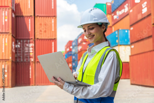Beautiful woman officer checking container cargo and holding laptop computer checking inventory. Female staff in logistics import and export shipping business concept.