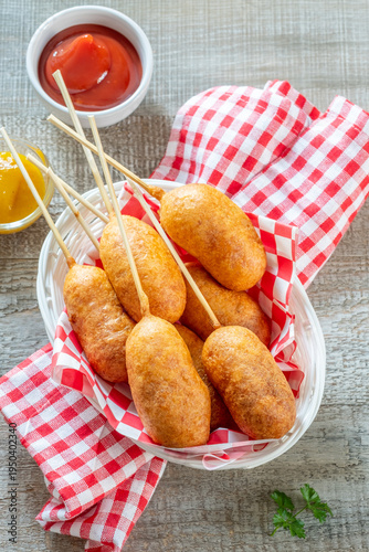 Eating corn dogs at a summer fair with friends while enjoying dipping sauces in the afternoon sun