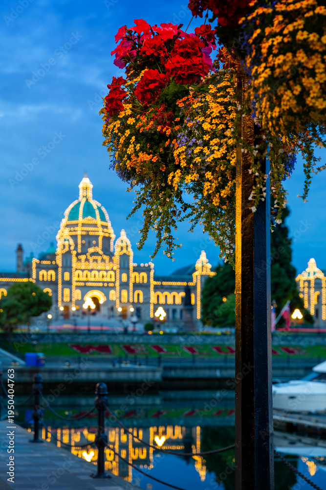 Fototapeta premium Victoria Parliament Building Inner Harbour Morning and Flower. Flower basket over Victoria's Inner Harbor and marina in downtown Victoria. The historic Legislative Building in the background. 