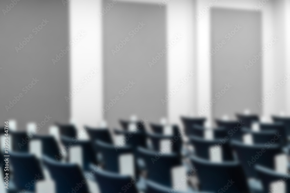 Fototapeta premium Empty blurred lecture hall with rows of blue ergonomic chairs and folding desks, ideal background for education, corporate training, academic seminars, and professional workshop presentations.
