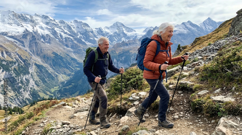 Elderly man and woman hiker with backpack trekking in mountain range during travel. Active seniors enjoying scenic nature landscape walk together. Outdoor lifestyle adventure vacation.