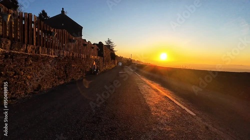 Driving along a country road at sunrise on a frosty UK winter morning, dazzled by the low rising Sun