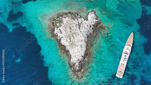 Aerial drone photo of luxury yacht anchored in paradise heart shaped island bay with turquoise crystal clear sea