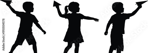 Black silhouette of three happy children playing together and throwing paper airplanes into the air against a clean white background isolated