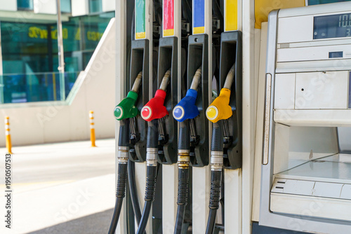 Fuel pump nozzles hanging at a modern gas station during a period of high oil prices. A conceptual photography showcasing the global energy crisis, increasing gasoline costs