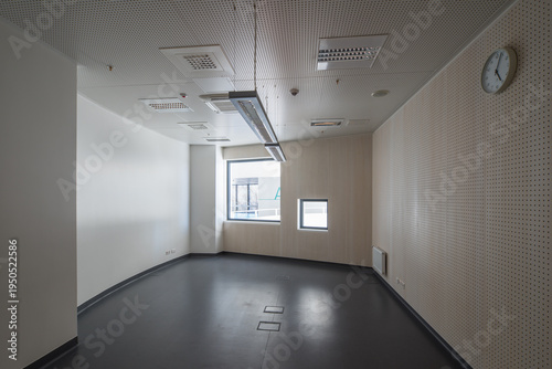 Modern hospital corridor interior with elevators and emergency exit signs.