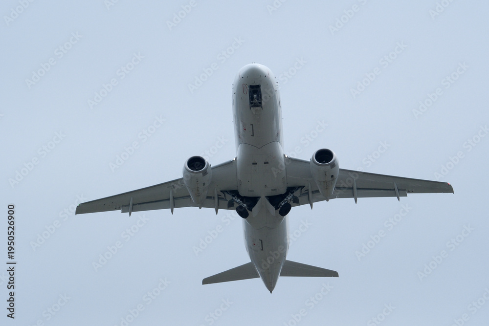 Fototapeta premium White passenger plane flying in cloudy sky. White aircraft against cloudy background, aviation travel