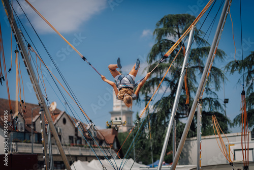 Foto Girl jumping upside down on bungee trampoline in amusement park