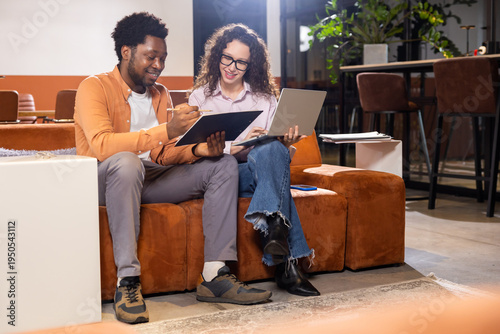 Happy woman and man with laptop and tablet working together in office