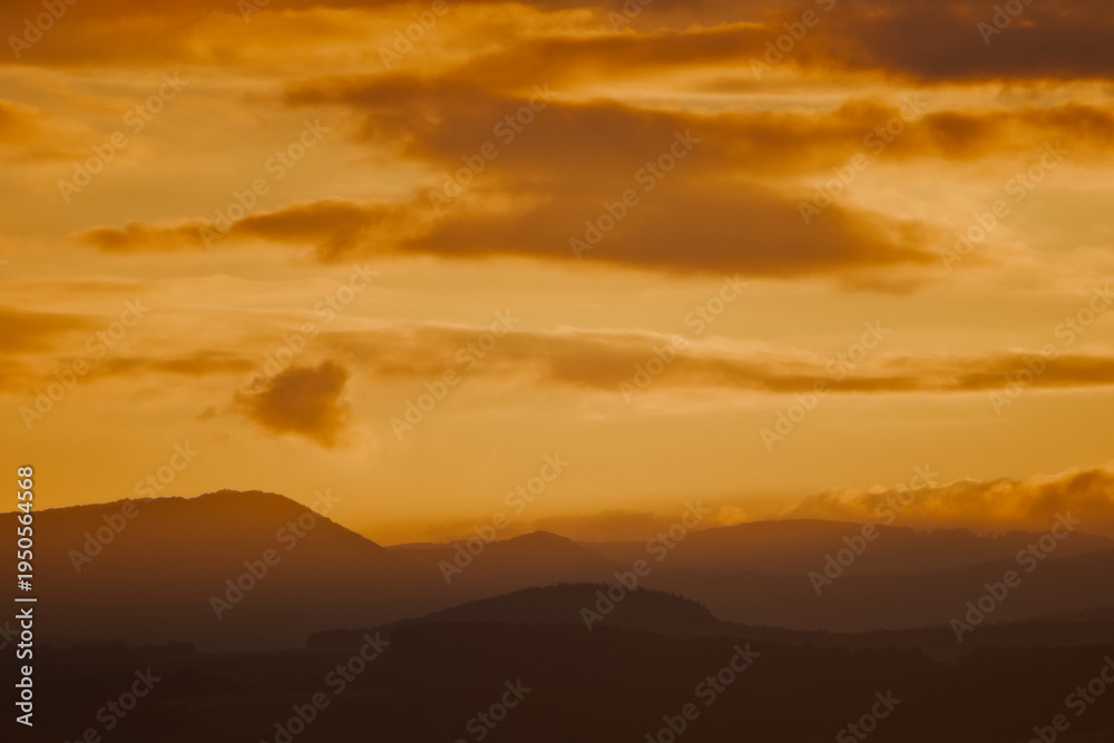 Fototapeta premium Warm Golden Sunset Over Dark Mountain Silhouettes