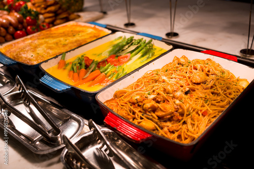 Billede på lærred Three hot dishes served on a buffet counter with detailed plating and fresh ingr