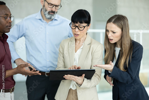Tableau sur toile Diverse business colleagues analyzing data on a tablet, showing confusion and co
