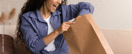 Photos A woman is smiling as she opens a brown paper bag