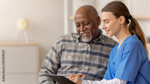 Canvas Print Healthcare worker sits with an older man in a medical office