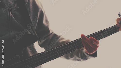 Strumming electric guitar. Musician plays music. Man fingers holding mediator. Man hand playing guitar neck in dark room