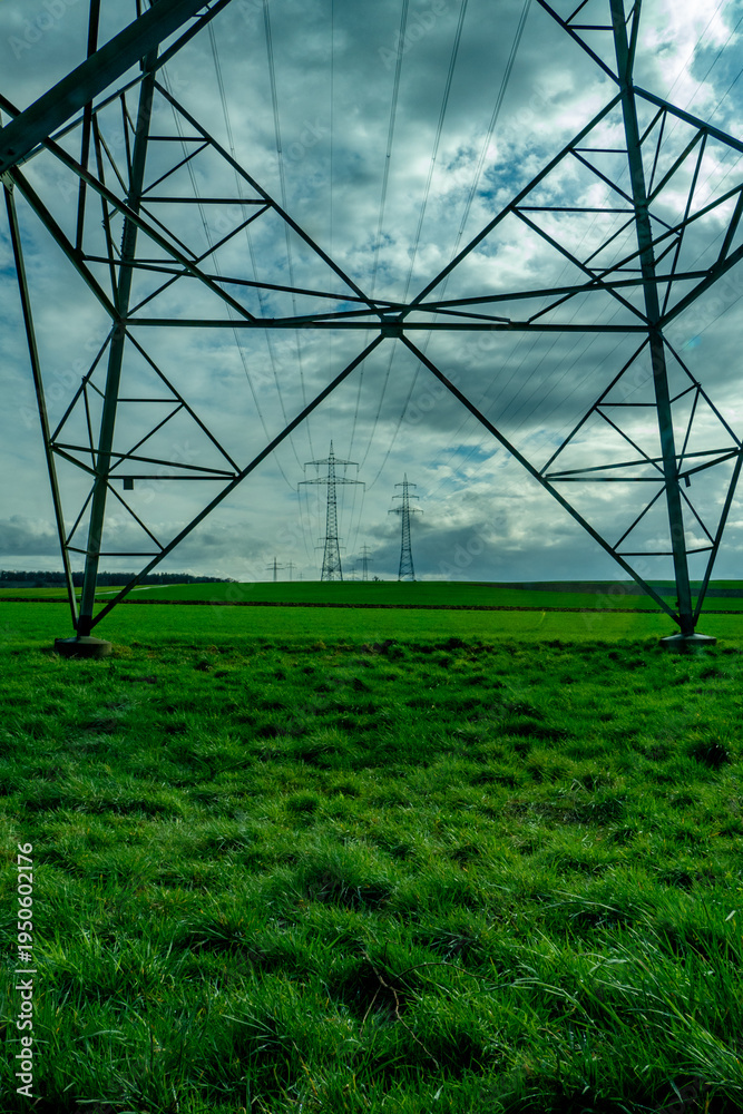 Fototapeta premium Strommasten unter einem stark bewölktem blauen Himmel