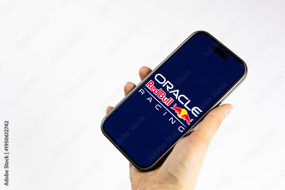 Fototapeta premium Moscow, Russia, March 14, 2026: Smartphone in hand showing Oracle Red Bull Racing logo on display, isolated on white background. F1 news about team new era with Red Bull Ford Powertrains
