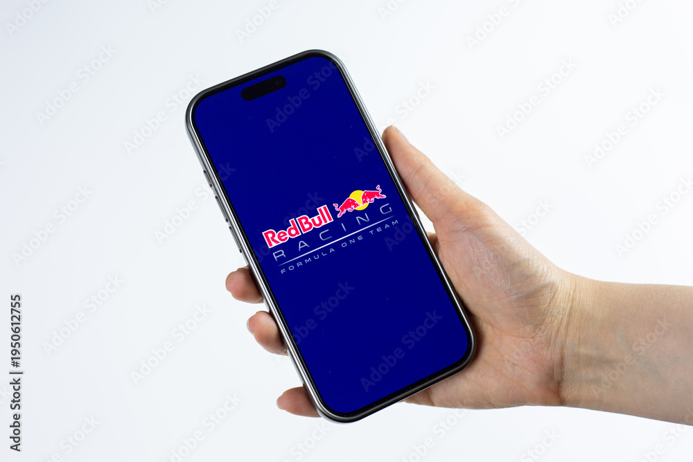 Naklejka premium Moscow, Russia, March 14, 2026: Hand holding smartphone displaying Red Bull Racing Formula 1 Team logo on screen, isolated on white background. Edge technology and innovation in Formula 1 motorsport